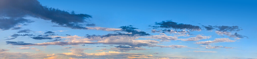Fototapeta premium Spectacular cumulus clouds at sunset. Three strands of wind-blown steam create a feathery layers thin horizontal sky above atmospheric front. Super detailed steam texture on deep blue background.