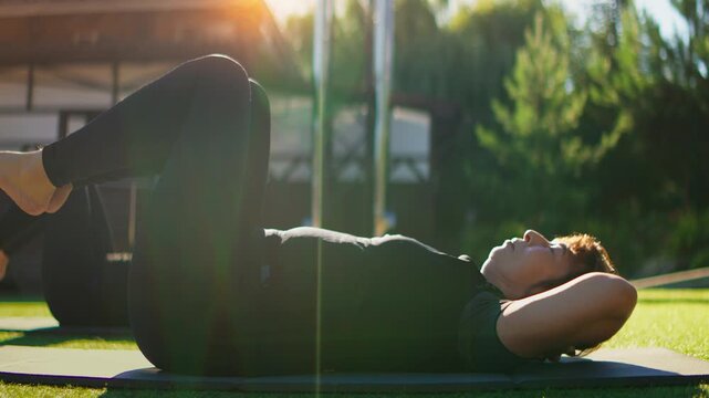 Elderly women practicing slow motion Pilates core exercises outdoors on grass mats, focusing on gentle fitness, flexibility, balance, and mindful body conditioning