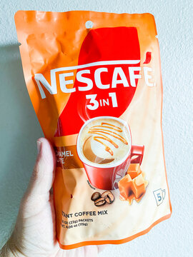 Hand holding an orange bag of Nescafe 3 in 1 Caramel Latte Instant Coffee Mix - August 06, 2026 Puyallup WA, USA