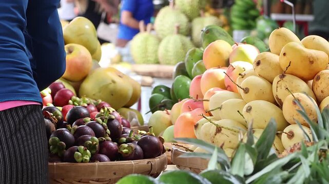 Fresh Tropical Fruits at Local Market Stall. Vendor Arranging Mangoes, Mangosteen, Pineapple and Exotic Produce for Sale, Healthy Food and Travel Concept.