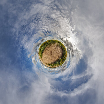 simple little tiny planet without buildings in blue sky with sun and beautiful clouds. Transformation of spherical panorama 360 degrees. Spherical abstract aerial view. Curvature of space.