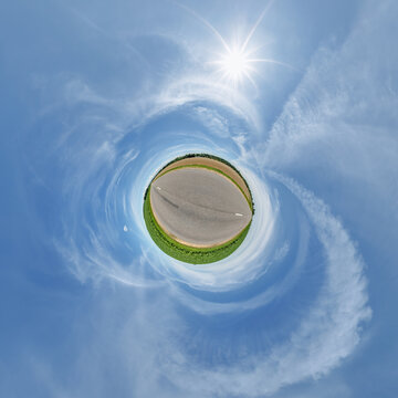 simple little tiny planet without buildings in blue sky with sun and beautiful clouds. Transformation of spherical panorama 360 degrees. Spherical abstract aerial view. Curvature of space.