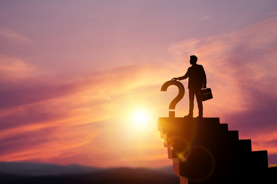 Silhouette of businessman holding question mark on top of stairs at sunset. Concept of business uncertainty, problem solving, decision making, and future strategy.