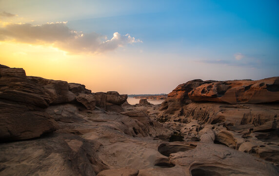 The rocks in the middle of the large river at sunset.
