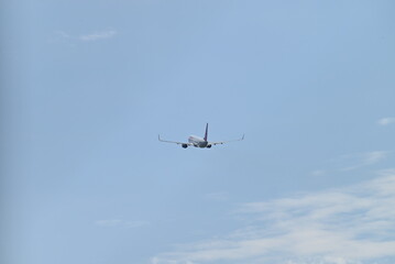Fototapeta premium 広大な青空へ向かって遠ざかる飛行機