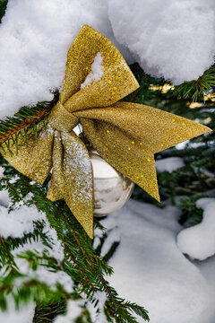 A decorated tree stands in the snow. A golden bow is tied to an ornament on the tree. This scene captures the spirit of Christmas in winter