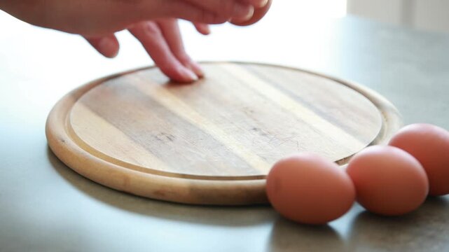 Close Up of Female Hands Peeling Hard Boiled Brown Egg on Wooden Cutting Board