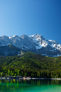 Travel landscape of Zugspitze Alps in Bavaria Germany, scenic summer nature panorama with forest, Eibsee lake, snow mountains peak. Alpine landscape