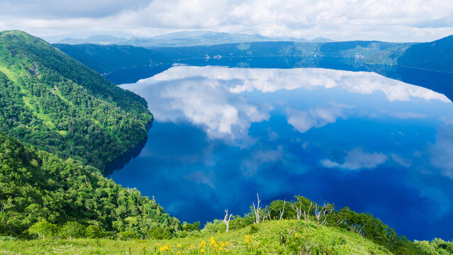 Forested volcanic rim surrounding the calm blue waters of Lake Mashu