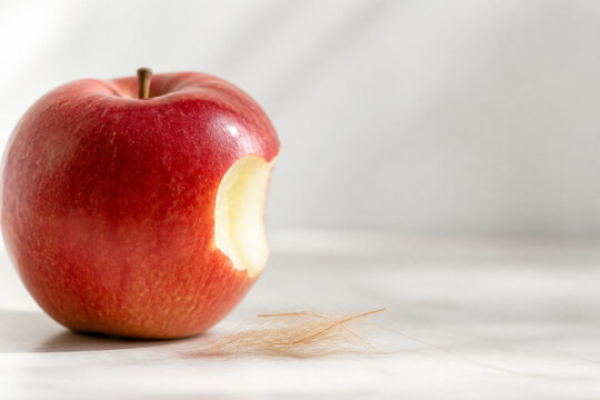 Ripe red apple with bite mark and wisps of fawn fur, safe and responsible food concept.