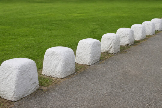 Row of white stone bollards and manicured lawn, boundary and landscaping concept