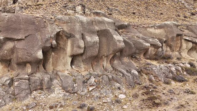 Aerial view of the rugged rock formations of Cordillera del Paine with weathered stone textures and sparse vegetation in Torres de Paine, Magallanes, Chile.