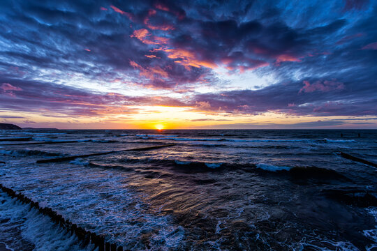 Scenic sundown on the sea shore with a breakwaters