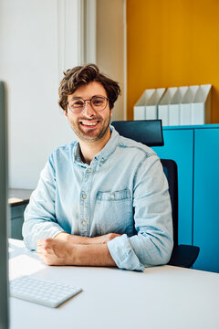 Smiling businessman sitting at desk in modern office