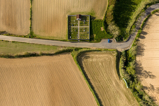 Aerial view of a cemetery surrounded by agricultural fields and a rural road in Maia, Acores, Portugal.