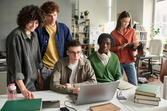 Diverse student team uses laptop during university class