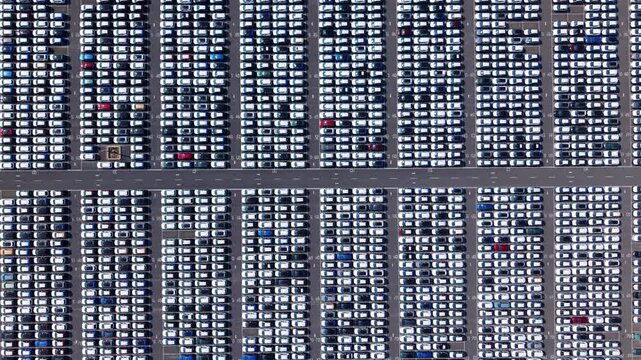 Aerial view of hundreds of uniform rows of new cars parked in a large distribution lot in Stallingborough, England, United Kingdom.