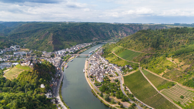 Aerial view of the Moselle river valley and historic Cochem with its Reichsburg castle, surrounded by lush vineyards, rolling hills, and the winding river in Cochem, Rhineland-Palatinate, Germany.