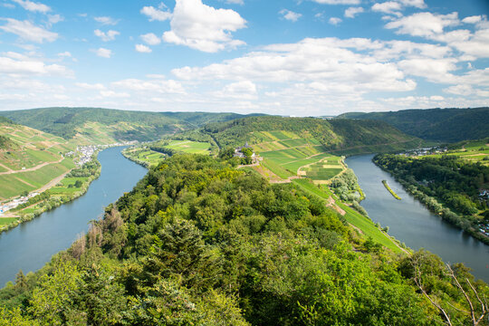 Aerial view of the Zeller Hamm and the Mosel river loop, featuring lush vineyards, the Petersberg, and the surrounding Eifel and Hunsrueck mountains in Zell, Rhineland-Palatinate, Germany.