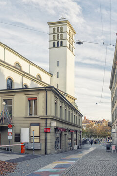 View of the historic Saint-Laurent church tower rising above a cobblestone street with a colorful painted path in the city center, Lausanne, Vaud, Switzerland.