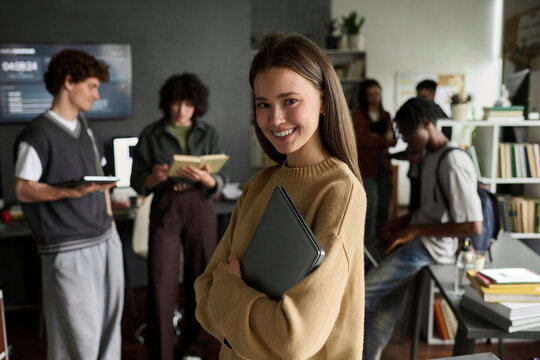 Cheerful female student holds a laptop in a university classroom
