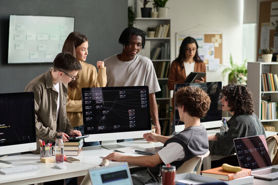 Diverse student group studies programming on computer in class