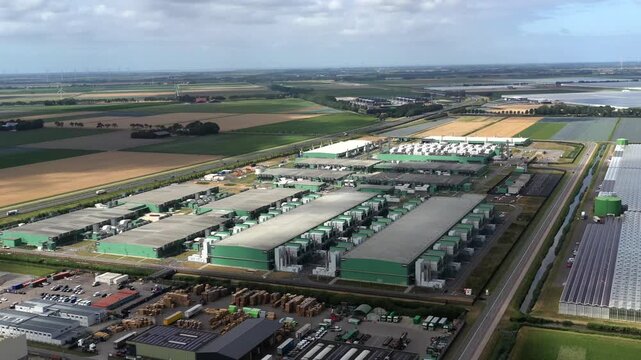 Aerial view of the Microsoft datacenter complex featuring large green industrial buildings surrounded by agricultural fields and infrastructure in Middenmeer, Noord-Holland, Netherlands.