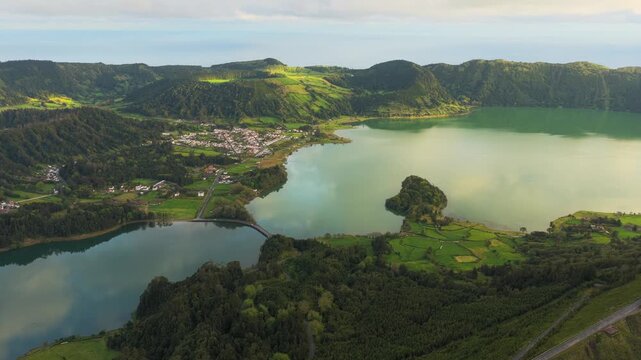 Aerial view of Sete Cidades volcanic crater lakes with lush green hills and a small village in Sete Cidades, Azores, Portugal.