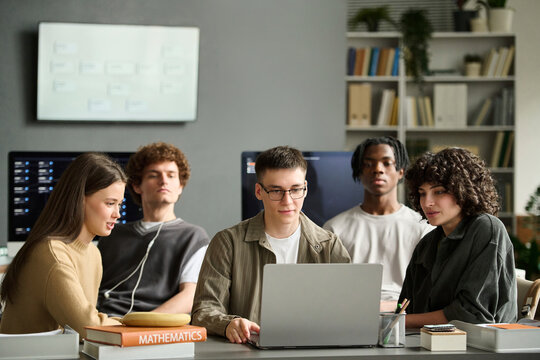 Diverse student group studies mathematics on laptop in classroom