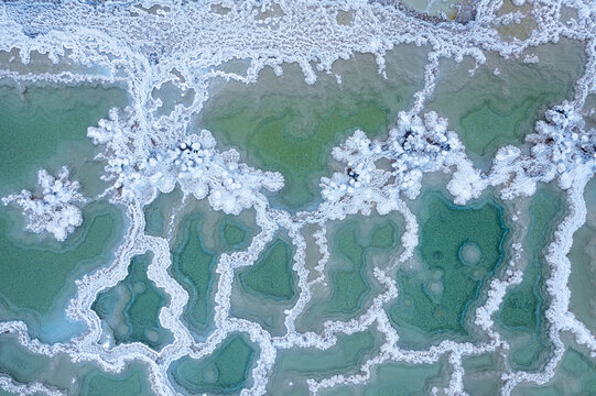 Aerial view of salt crystal formations in the turquoise waters of the Dead Sea, showcasing intricate white patterns and mineral deposits in Beersheba, South District, Israel.