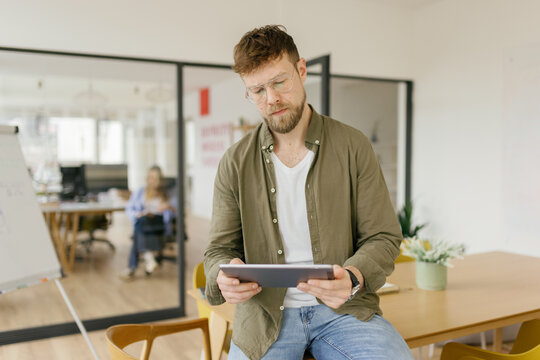 A thoughtful businessman uses a tablet in a modern office