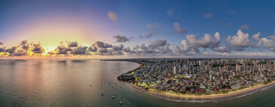 Aerial view of the coastal skyline of Joao Pessoa at sunset with golden light reflecting on the ocean and clouds over the beach in Joao Pessoa, Paraiba, Brazil.