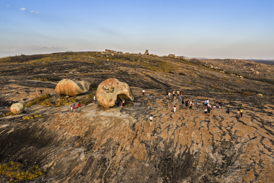 Aerial view of Lajedo de Pai Mateus, a unique rock formation with large granite boulders on a vast rocky plateau, with tourists walking in Cabaceiras, Paraiba, Brazil.