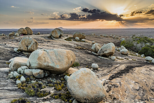 Aerial view of Lajedo de Pai Mateus with its iconic large granite boulders scattered across the rocky landscape under a golden sunset sky in Cabaceiras, Paraiba, Brazil.