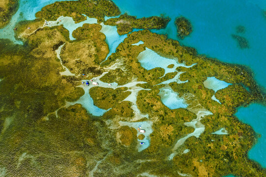 Aerial view of Piscinas naturais em Ponta do Seixas with vibrant coral reefs, shallow turquoise waters, and small boats anchored in the clear sea, Joao Pessoa, State of Paraiba, Brazil.