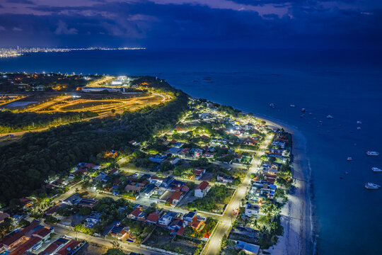 Aerial view of Seixas Beach at night with illuminated streets and houses along the coastline in Joao Pessoa, Paraiba, Brazil.
