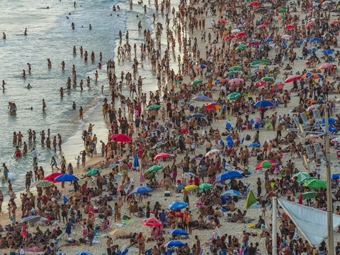 Aerial view of Ipanema beach crowded with people, colorful umbrellas, and swimmers in the Atlantic Ocean in Rio de Janeiro, Rio de Janeiro, Brazil.