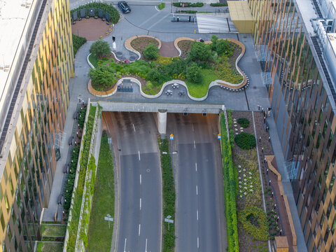 Aerial view of a modern office complex featuring a green roof bridge over a road tunnel with lush landscaping and contemporary glass architecture in Krakow, Lesser Poland Voivode, Poland.