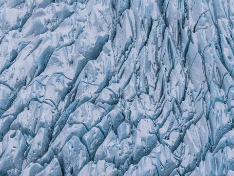 Aerial view of the intricate blue ice textures and deep crevasses of the Fjallsarlon glacier in Sveitarfelagid Hornafjordur, Iceland.
