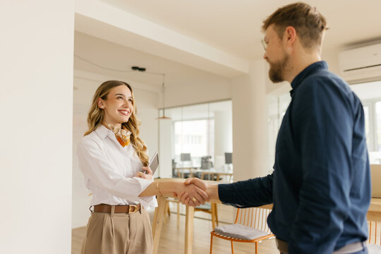 Smiling businesswoman and businessman shake hands in the office