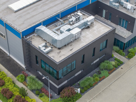 Aerial view of a modern logistics hub with a flat roof featuring HVAC systems, dark facade, and glass windows, surrounded by landscaping in Krakow, Lesser Poland Voivode, Poland.