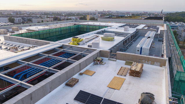 Aerial view of an AI data center rooftop featuring HVAC cooling systems, industrial piping, and solar panels under construction in Krakow, Lesser Poland Voivode, Poland.