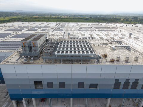 Aerial view of the Lidl logistics center under construction, featuring a large flat roof with HVAC units and solar panels in Skawina, Lesser Poland Voivode, Poland.