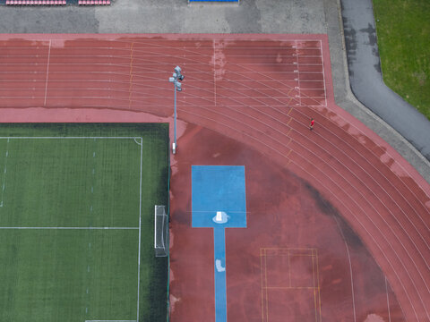 Aerial view of the Malopolska Arena Lekkoatletyczna with a red running track and green field in rainy weather in Wieliczka, Wojewodztwo malopolskie, Poland.