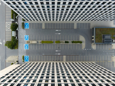Aerial view of modern office buildings with grid facades flanking a parking lot with marked spaces and green planters in Krakow, Lesser Poland Voivode, Poland.