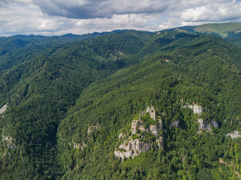 Aerial view of the rocky outcrops above Bystricka dolina in the Velka Fatra mountains, surrounded by dense green forests under a cloudy sky in Dolny Harmanec, Banskobystricky kraj, Slovakia.