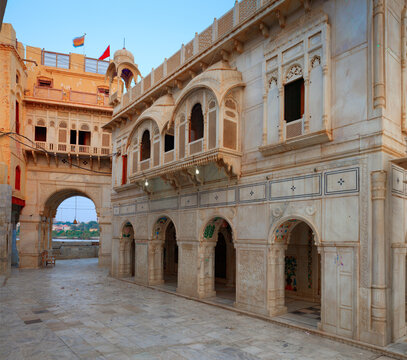 View of the historic Sadhu Bela Mandir temple complex featuring intricate white marble architecture, arched doorways, and traditional balconies in Rohri, Sindh, Pakistan.