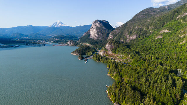 Aerial view of the Stawamus Chief monolith rising above the forested coastline and the waters of Howe Sound in Squamish, British Columbia, Canada.