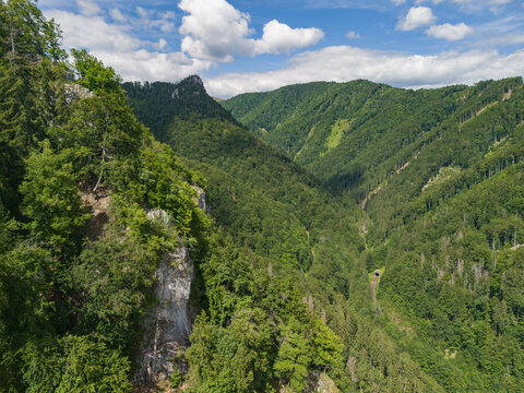 Aerial view of Bystricka dolina in the Velka Fatra mountains, featuring lush green forests, rocky cliffs, and a winding valley landscape in Dolny Harmanec, Banskobystricky kraj, Slovakia.