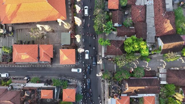 Aerial view of Pura Agung Petilan with traditional orange tiled roofs and busy traffic at an intersection in Kecamatan Denpasar Timur, Bali, Indonesia.